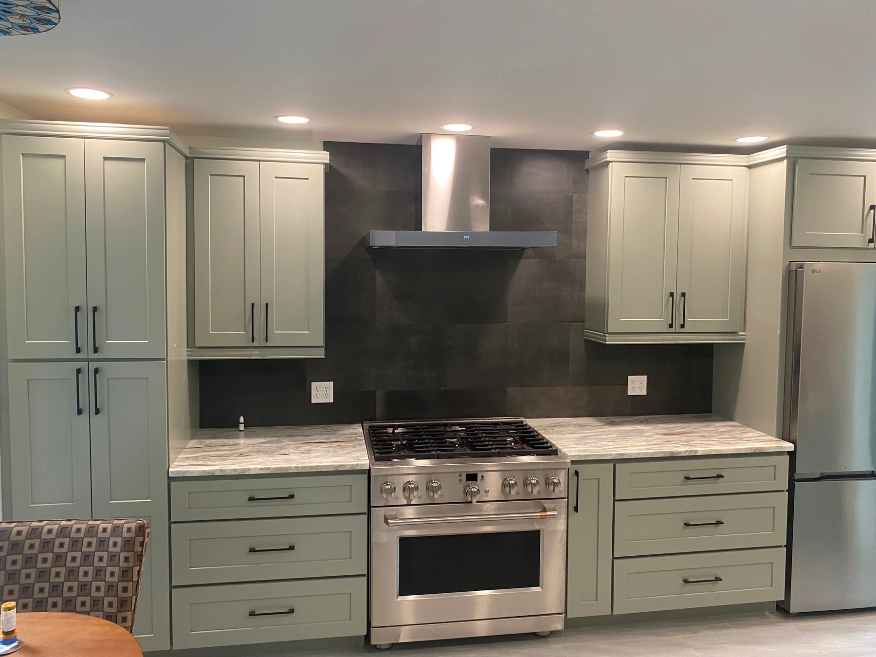 Albany kitchen remodel with sage cabinetry, range hood, tile backsplash, and stone countertops by Weber Carpentry & Home Improvement